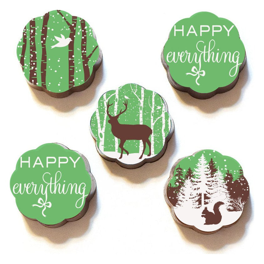 Five Chouquette Woodland Wonderland chocolate caramels with green tops: a bird, a deer and a squirrel in snowy woods, plus two Happy Everything script pieces