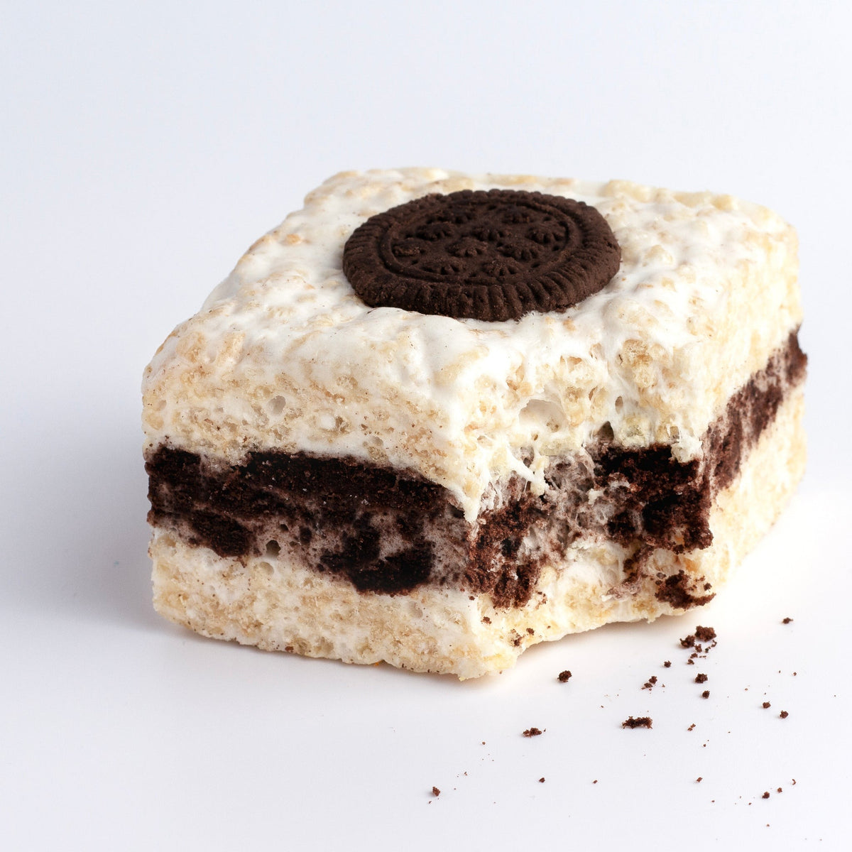 The Crispery Cookies & Cream Crispycake with a bite taken from the corner, showing the cookie layer inside the marshmallow and crisped rice