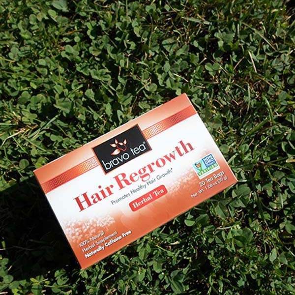 Bravo Tea Hair Regrowth herbal tea box tilted on green clover