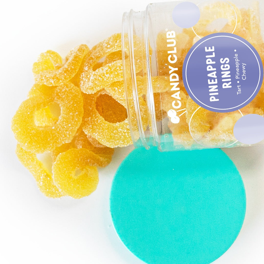 Candy Club Pineapple Rings cup tipped on its side with yellow gummy rings spilling out next to its teal lid
