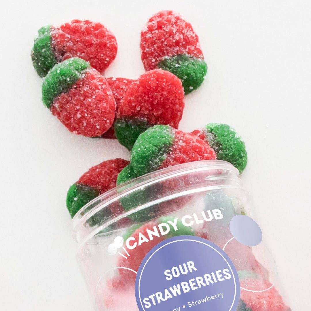 Candy Club Sour Strawberries cup tipped on its side with strawberry-shaped sour gummies spilling out