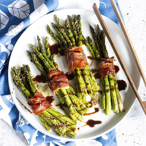 Serving suggestion: prosciutto-wrapped asparagus bundles seasoned with Urban Accents Citrus Pepper Veggie Roaster on a white plate