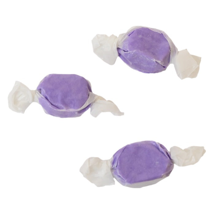 Three wrapped pieces of Sweet's Huckleberry taffy in solid purple on a white background