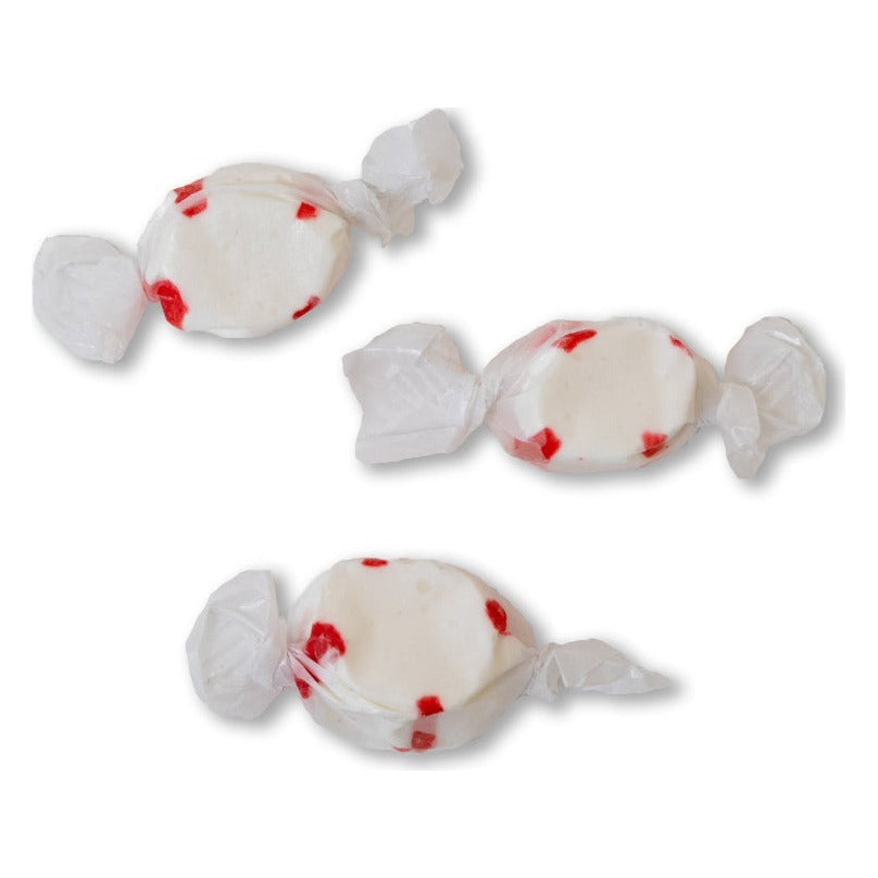 Three wrapped pieces of Sweet's Peppermint taffy, white with red stripes, on a white background