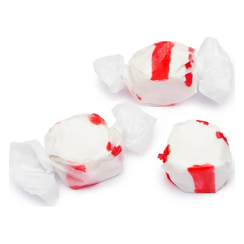 Two wrapped and one unwrapped piece of white Peppermint salt water taffy with red stripes