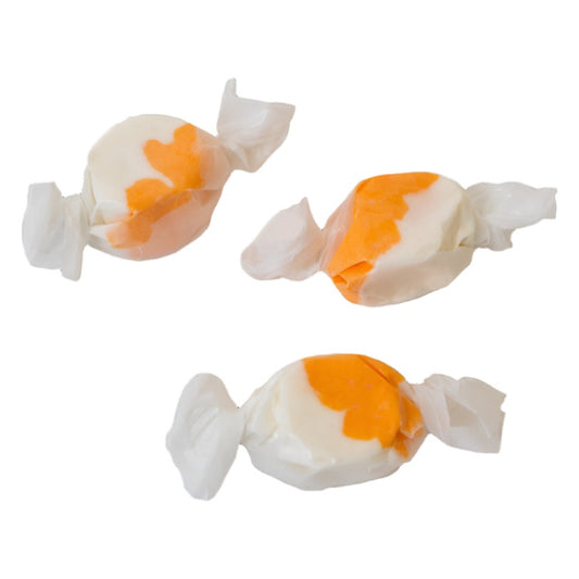 Three wrapped pieces of Sweet's Orange Vanilla taffy, white with an orange section, on a white background