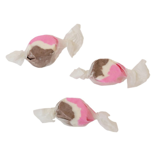 Three wrapped pieces of Sweet's Neapolitan taffy, each with brown, pink and white sections, on a white background