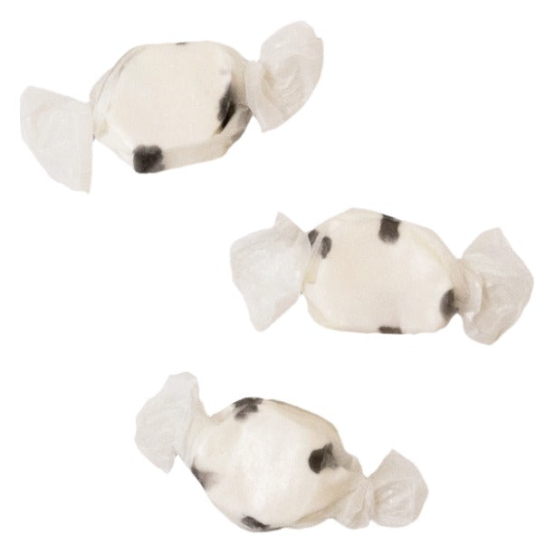 Three wrapped pieces of Sweet's Black Licorice taffy, cream-white with black marks, on a white background