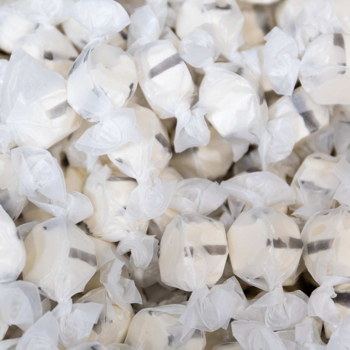 Close-up of a pile of wrapped Sweet's Black Licorice taffy, white pieces with a black stripe