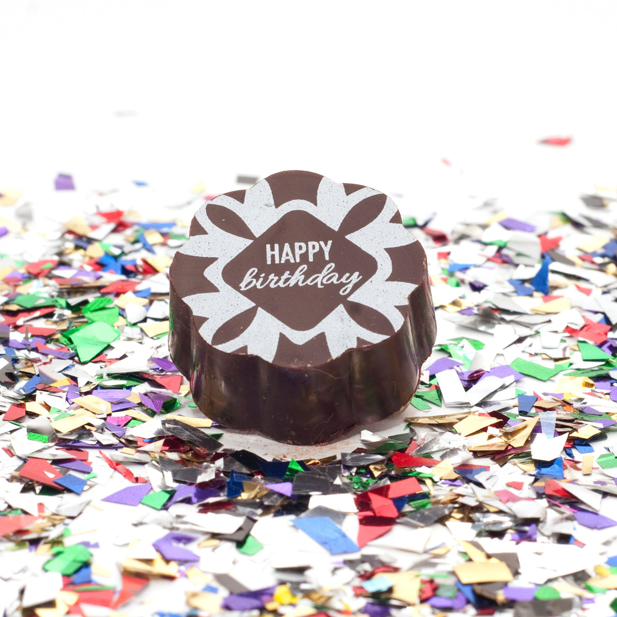 Chouquette Birthday chocolate caramel with a script Happy birthday on a white starburst design, on confetti