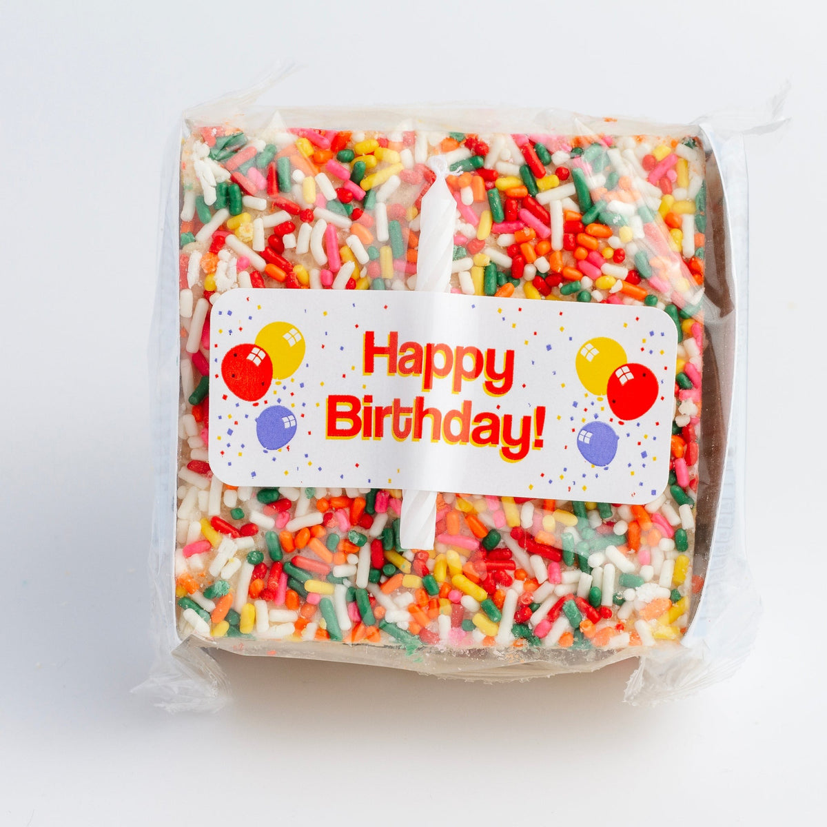 Top view of the wrapped Happy Birthday Crispycake showing the Happy Birthday label and the white candle sealed under the cellophane
