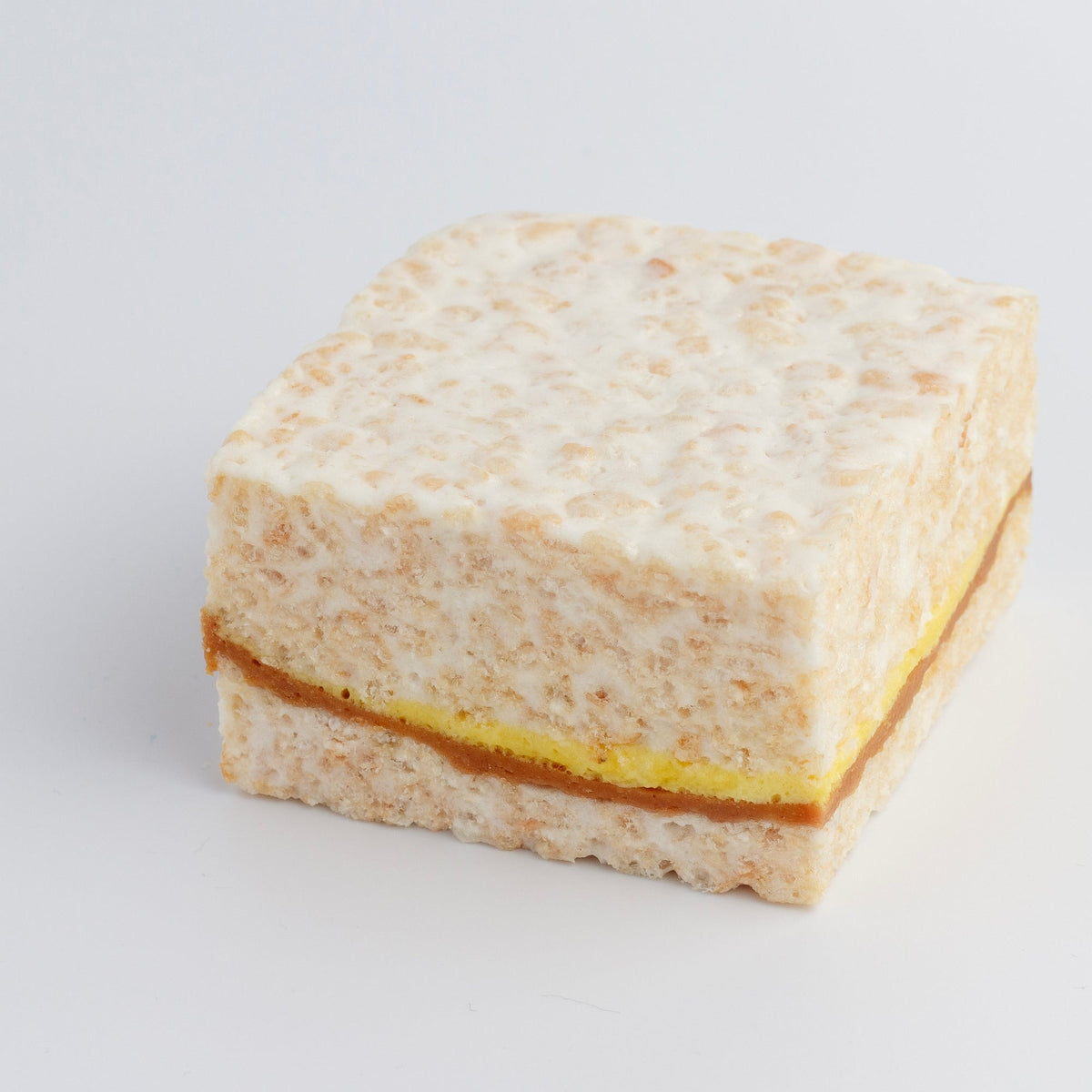 Peanut Butter & Banana Crispycake on a white background showing the peanut butter and yellow banana layer through the middle