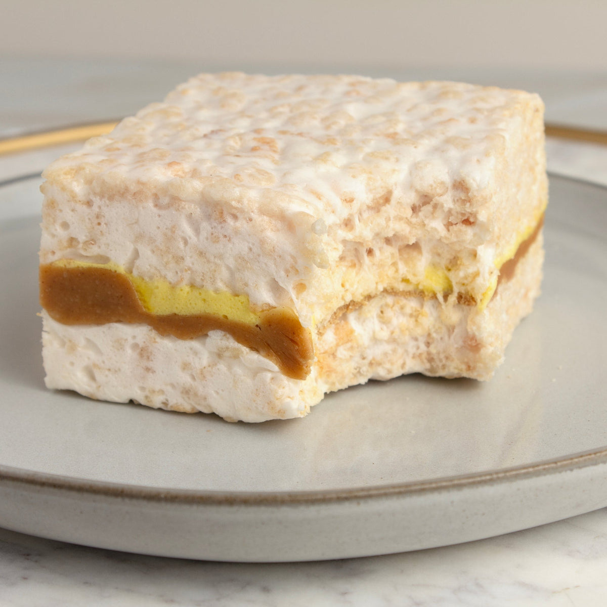 Peanut Butter & Banana Crispycake with a bite taken out, on a gray plate