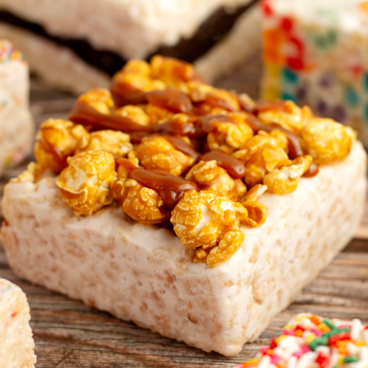 Close view of a Popcorn Crunch Crispycake on a wooden table showing the popcorn topping and drizzle