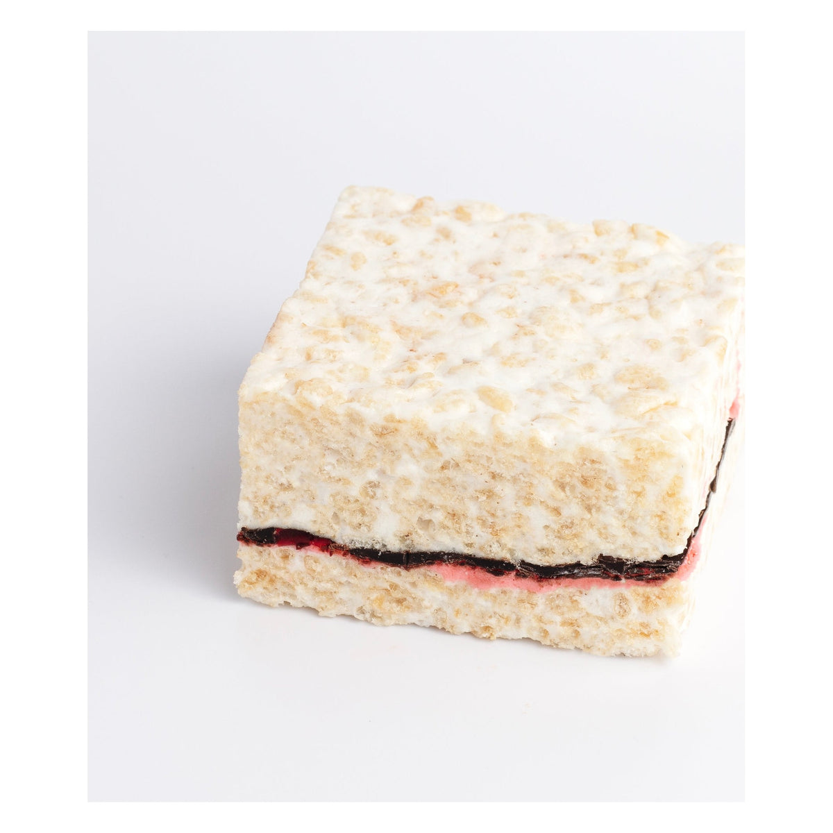 Raspberry Chocolate Crispycake on a white background showing the chocolate and pink raspberry layers through the middle