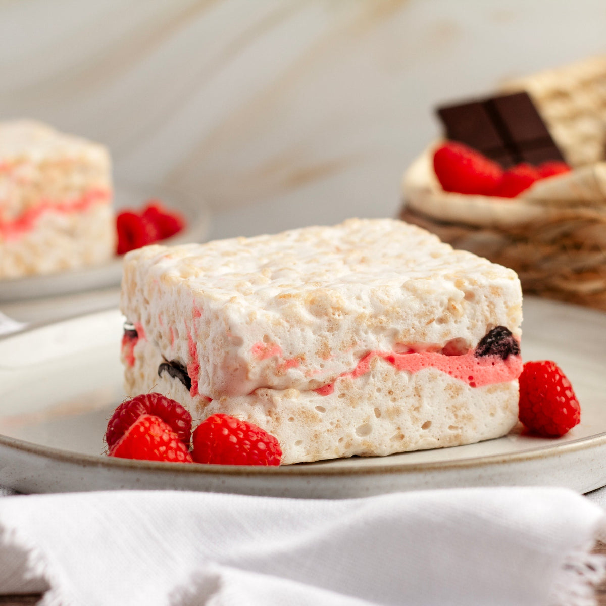 Raspberry Chocolate Crispycake on a plate with fresh raspberries and chocolate in the background
