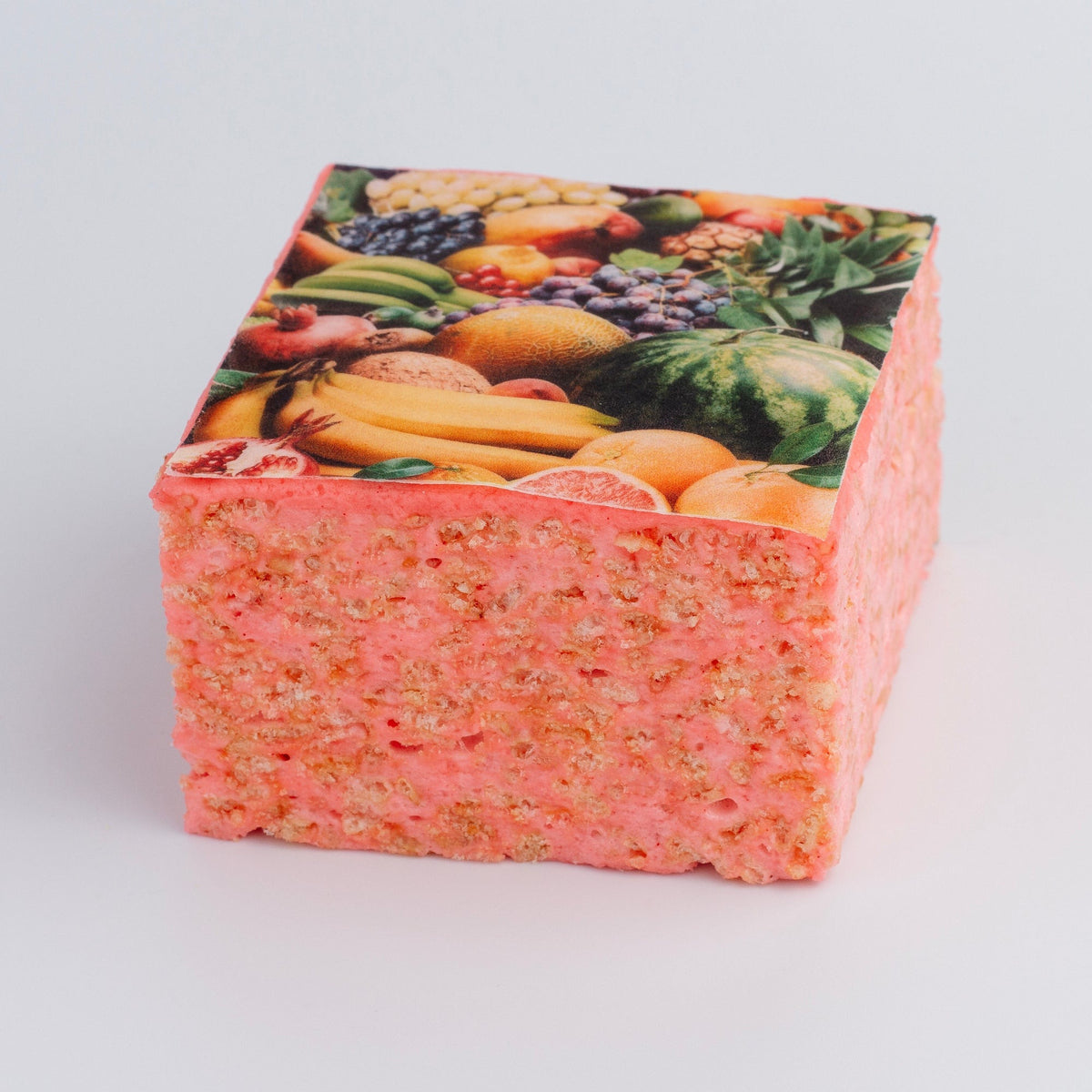 The Crispery Tropical Fruit Crispycake on a grey background, showing the printed assorted-fruit top and the crispy rice and marshmallow sides