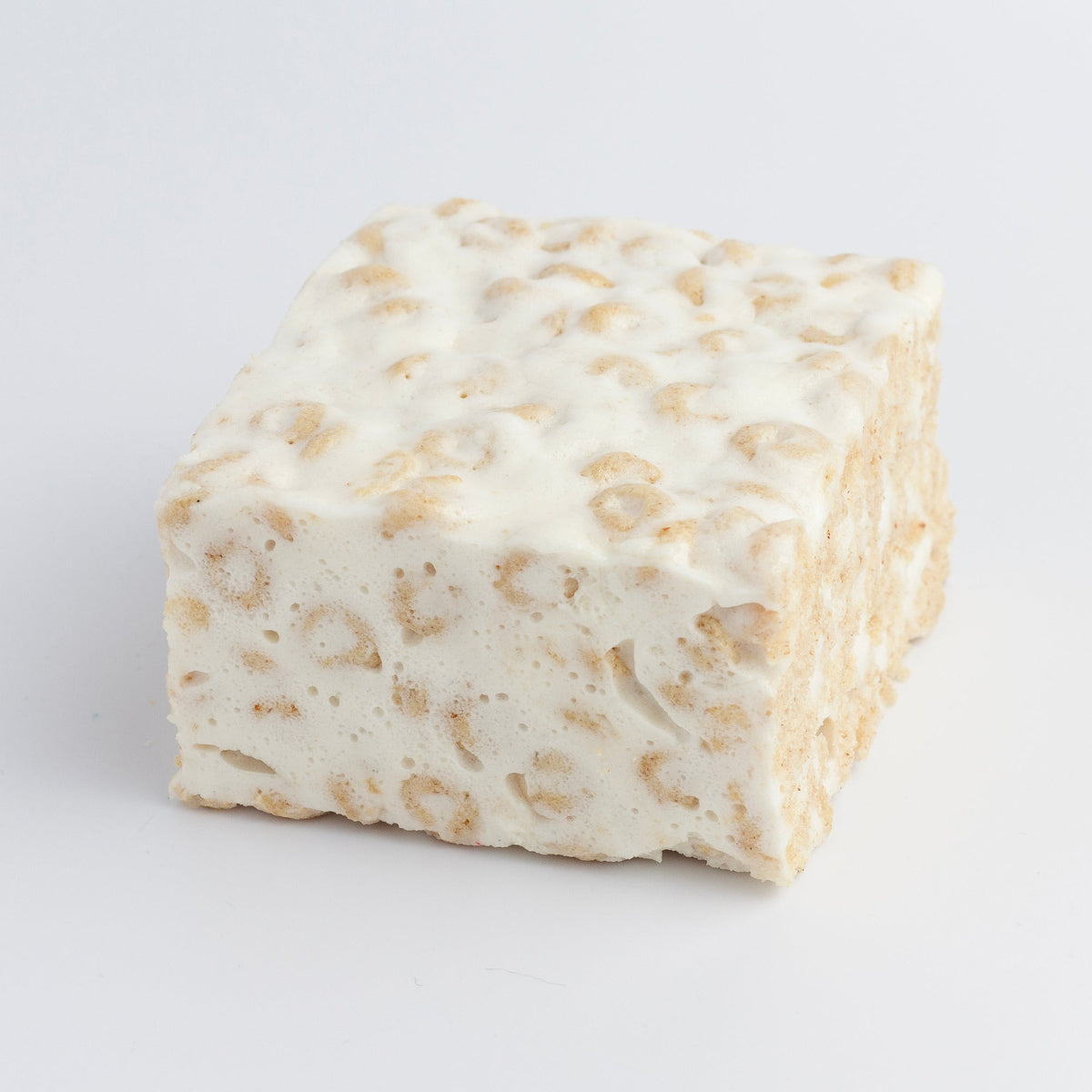 The Crispery Honey Nut Crispy Crispycake on a grey background, with oat O cereal visible through the marshmallow