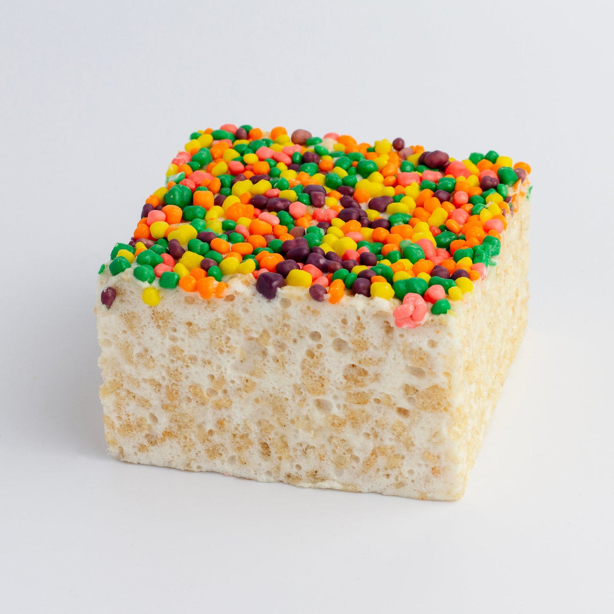 The Crispery Nerdtastic Crispycake on a grey background, its top covered in tiny multicolored candies