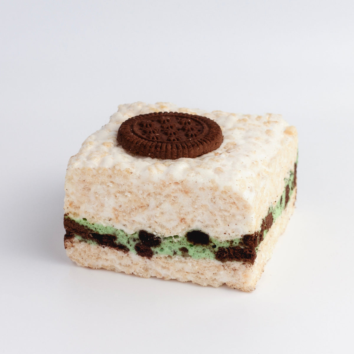 Mint Cookies & Cream Crispycake on a light gray background showing the green mint cream and chocolate cookie layer and a chocolate cookie on top