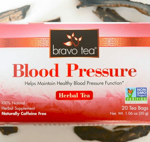 Close-up of the Bravo Blood Pressure Herbal Tea box showing the Non-GMO Project Verified seal and 20 Tea Bags, with dried herbs behind it
