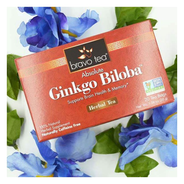 Bravo Tea Absolute Ginkgo Biloba box lying among blue iris flowers and green leaves