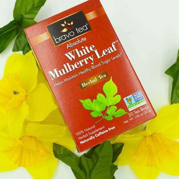 Bravo Tea Absolute White Mulberry Leaf box with the green mulberry leaf artwork, set among yellow daffodils