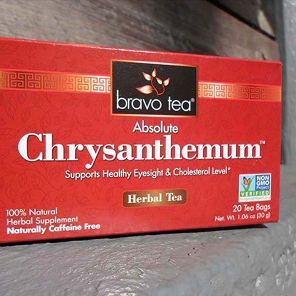 Bravo Tea Absolute Chrysanthemum box on its side on a wooden step, showing 20 tea bags and Net Wt. 1.06 oz