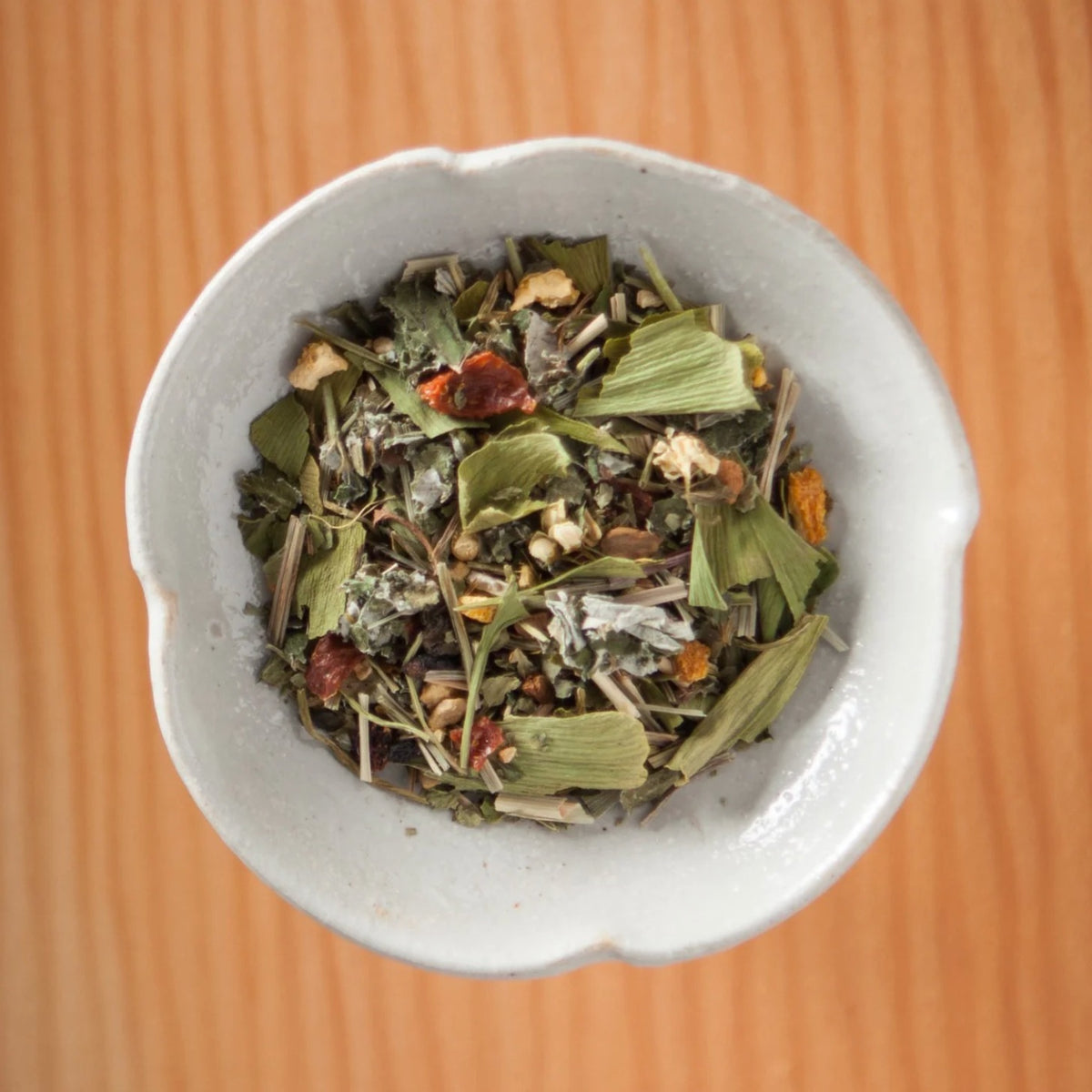 Dry Bluebird Morning tea blend in a bowl on a wooden table, showing the loose leaves and herbs inside the tea bags