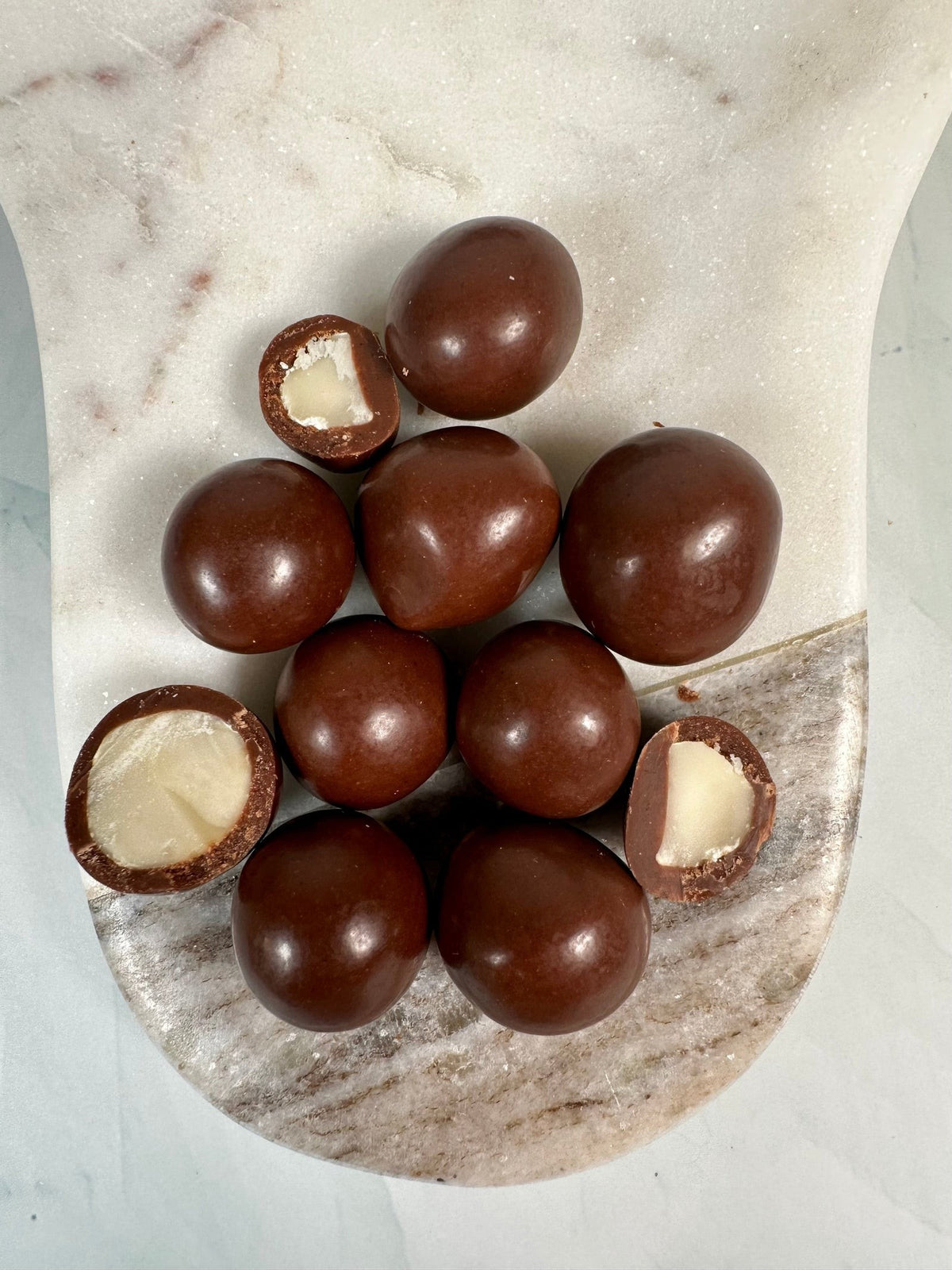 Close-up of Windy City Organics Rawmio Oat Milk Chocolate Covered Macadamia Nuts as it comes out of the package